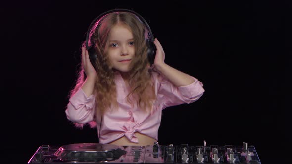 Little Girl Dj in Headphones Playing on Vinyl. Black Background