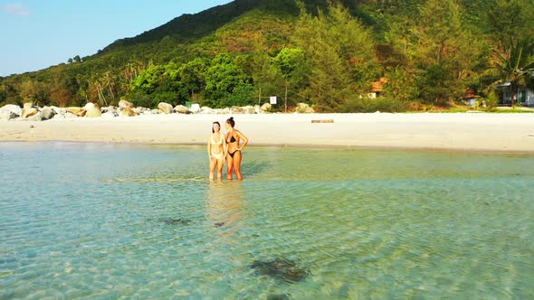 Beautiful ladies best friends on perfect island beach trip by blue green ocean and white sand backgr