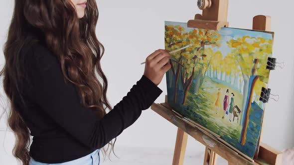 Young Woman Artist Painting Picture on Canvas in Art Studio