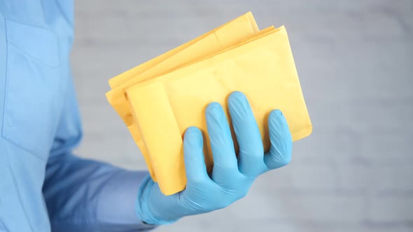 Hand in Latex Gloves Holding White Paper Bubble Envelope for Postal Ship