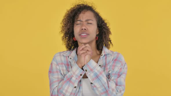 Praying Young African Woman Wishing on Yellow Background