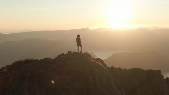 Adventurous Caucasian Woman Hiking on Top of a Rocky Mountain Cliff