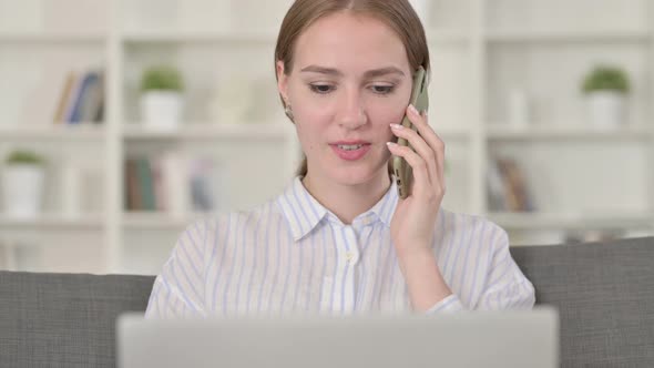 Portrait of Young Woman with Laptop Talking on Smartphone 