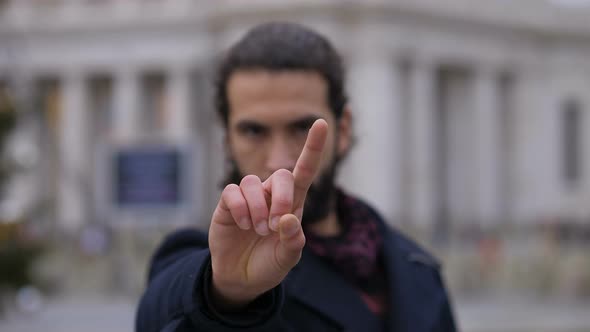 Young man making "no" gesture in the street. Denial, refusal