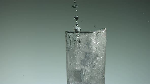 Carbonated liquid pouring into glass filled with ice