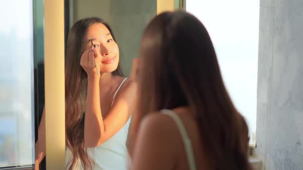 Young asian woman check her face on mirror