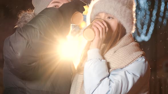 Young Couple in the City During Christmas Drink Hot Coffee