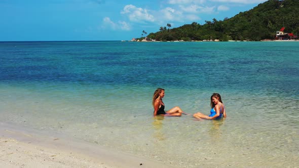 Girls relaxing on exotic tourist beach lifestyle by clear ocean and white sandy background of Thaila