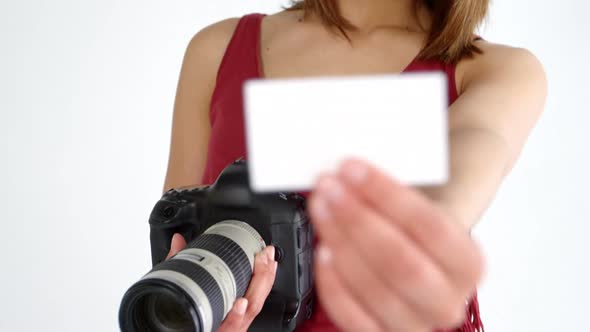 Photographer showing visiting card while taking photo with digital camera