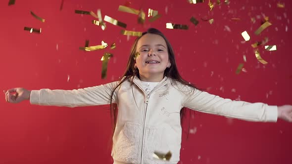 Teen Girl Dressed in Stylish Clothes Throwing Confetti on the Red Background