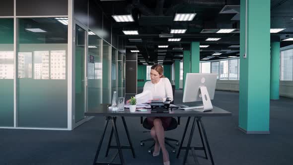 Working Overtime Businesswoman Sits at a Desk in the Office and Works on a Pc Manager Works on