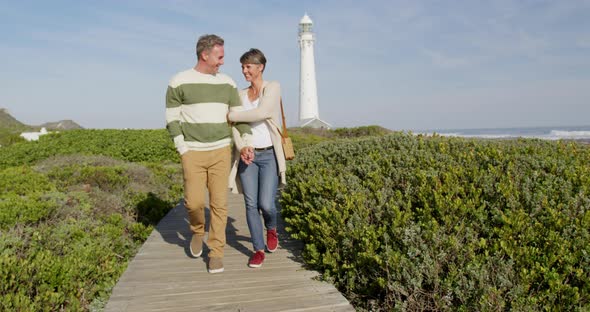 Caucasian couple enjoying free time by sea on sunny day walking path