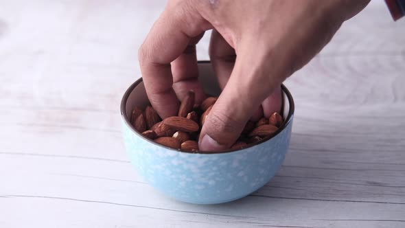Close Up of Hand Picking Almond From a Bowl 