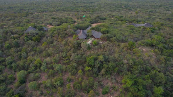 aerial shot over african lodges into primary savannah landscape