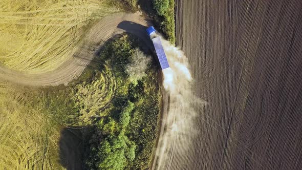 Top Down Aerial View of Fast Driving Car on Dirt Road Leaving Cloud of Dust Behind