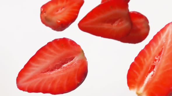 Super Closeup of the Ripe Halves of Strawberries Falling on a White Background