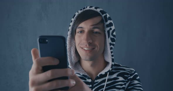 Portrait of Young Man in Kigurumi Zebras Using Smartphone