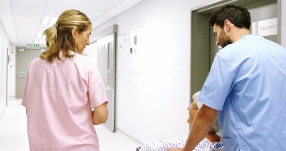 Nurse pushing a patient in a wheelchair while talking to a doctor