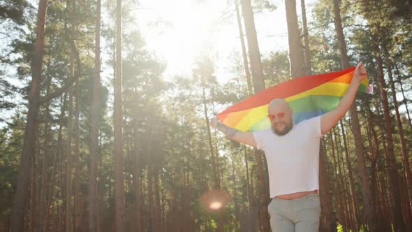 Happy Queer Man Waving Rainbow Gay Flag on Sun Flare Light in Beautiful Summer Day. Happy Guy