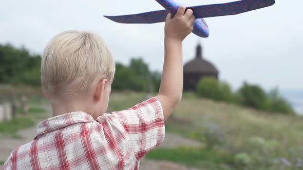 A Boy with an Airplane in His Hands Runs in the Park