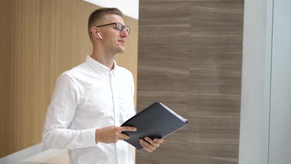 Businessman Speaking In Wireless Earphones In Corporate Office Lobby