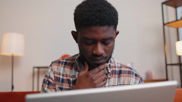 African American Man Sitting on Sofa Opening Laptop Pc Starting Work Online in Living Room at Home