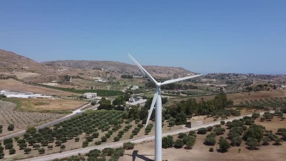 Aerial view: wind turbine turning in wind on mediterranean hillside