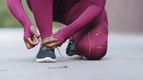 African Black Female Hands Tying Shoelace on Running Shoes Before Practice
