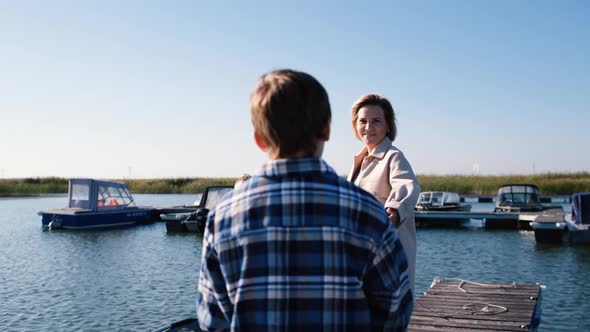 An Adult Woman Mother Sees Off Her Husband and Son on a Fishing Trip in the Sea on a Boat Standing