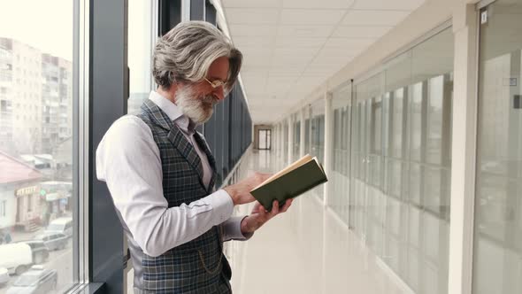 Mature Businessman in Suit Reading in the Airport Terminal