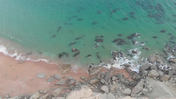 Aerial close up shot of jiwani beach with waves crashing rocks in Balochistan. The sea and the shore
