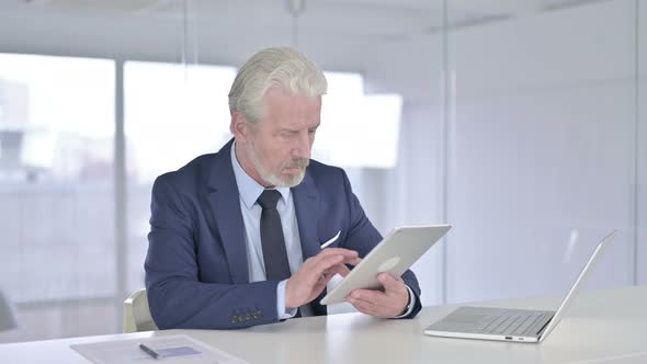 Old Businessman Using Tablet in Office