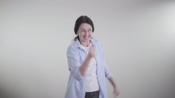 Excited Caucasian Woman Making Victory Gesture, Spinning and Dancing on White Background. Portrait