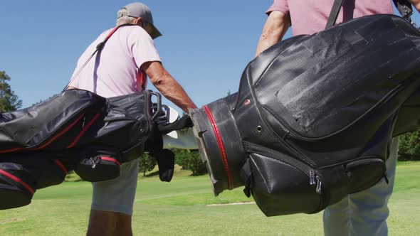 Two caucasian senior man wearing face masks walking with their golf bags at golf course