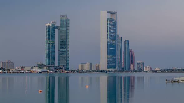 Abu Dhabi City Skyline with Skyscrapers Before Sunrise with Water Reflection Night to Day Timelapse