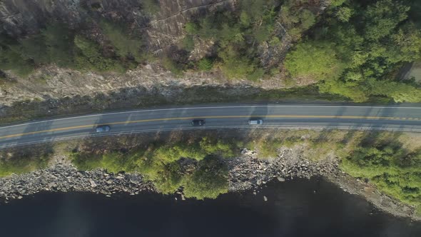 Cars Are Going on Country Road Near Lake in Norway in Summer Day. Aerial Vertical Top-Down View