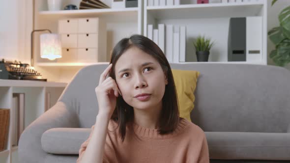 Young Asian woman sitting on sofa and thinking have idea.