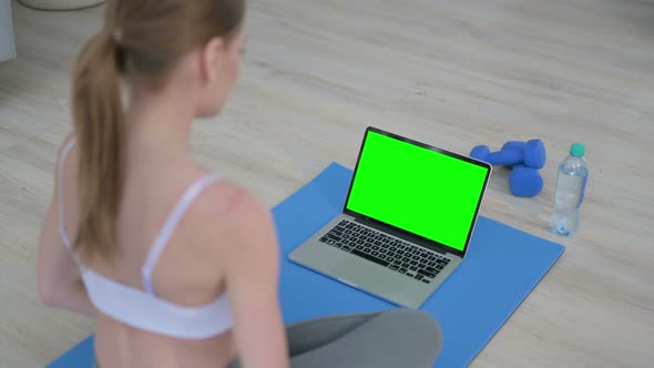 Rear View of Young Woman Doing Yoga While Looking at Laptop with Chroma Key Screen