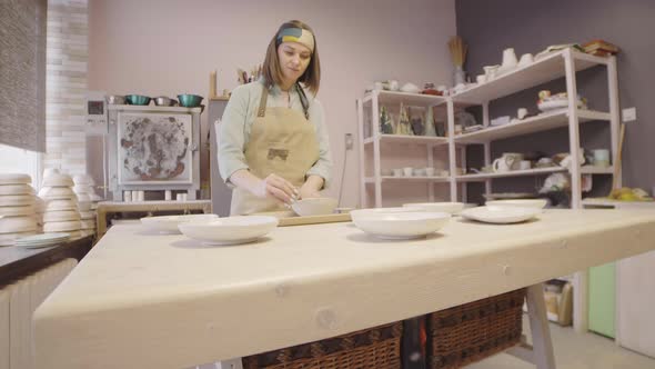 Caucasian Woman Sanding Clay Bowl