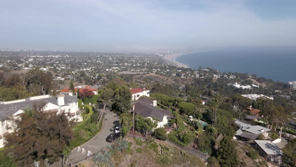 Aerial fly over mansions overlooking Santa Monica and beach