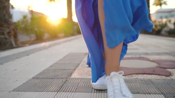 Legs of a Woman in a Beautiful Blue Dress Walking Along the Palm Avenue
