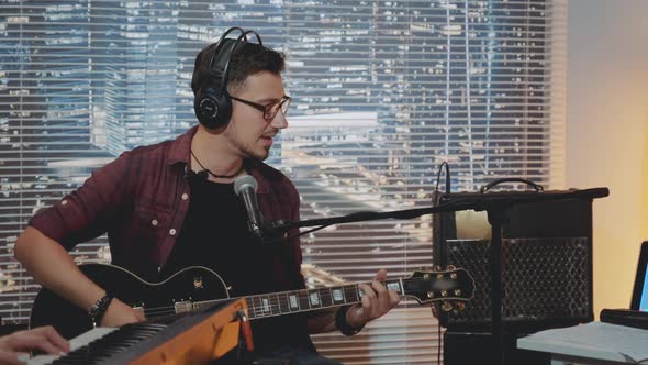 Musician in Headphone and Trendy Casual Clothes Recording His New Song in Home Studio