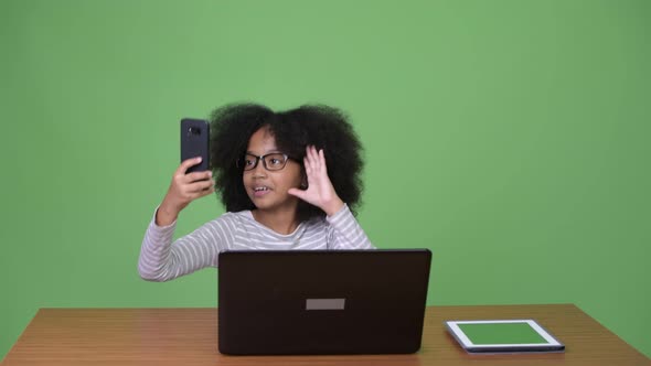 Young Cute African Girl with Afro Hair Using Laptop