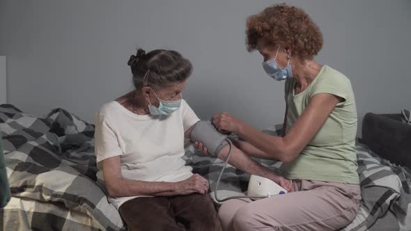 Mature Woman Wearing Face Masks Measuring Blood Pressure of Senior Elderly Female During Outbreak