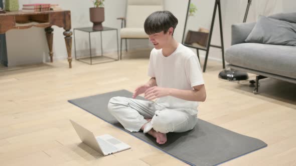 Young Asian Man Using Laptop on Yoga Mat at Home