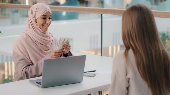 Young Friendly Smiling Arab Woman Manager Sits in Office at Desk Communicates with Client Explains