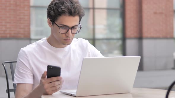 Young Man Using Smartphone and Laptop Outdoor