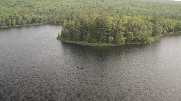 Wide aerial high above lake with canoe surrounded by wilderness