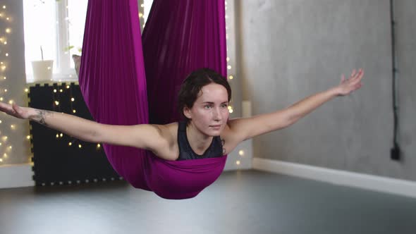 Young Woman Hanging on the Purple Yoga Hammock