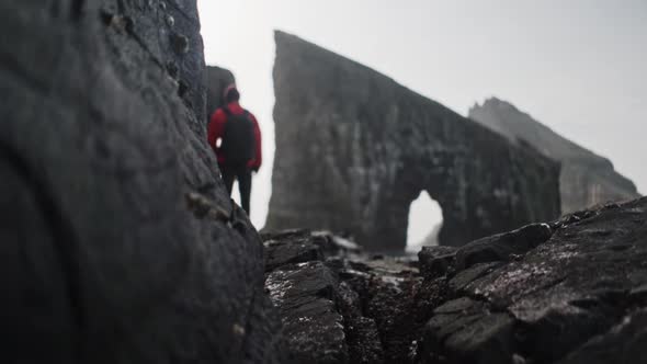 Male Traveler Looking at the Beautiful Drangarnir Sea Stack in Faroe Islands
